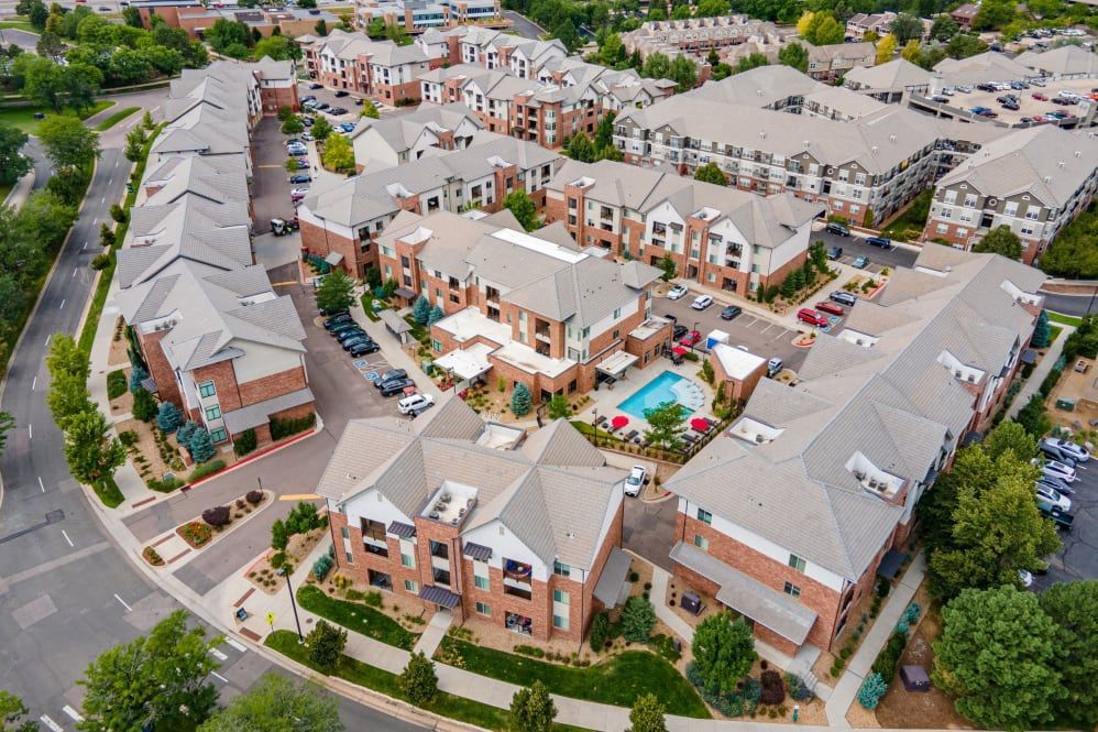 Aerial view of apartment complex with multiple buildings, pool, and parking.