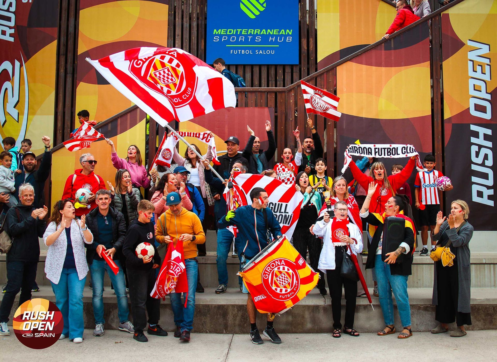 Fans cheering with red flags outside a stadium entrance with a “Rush Open” sign