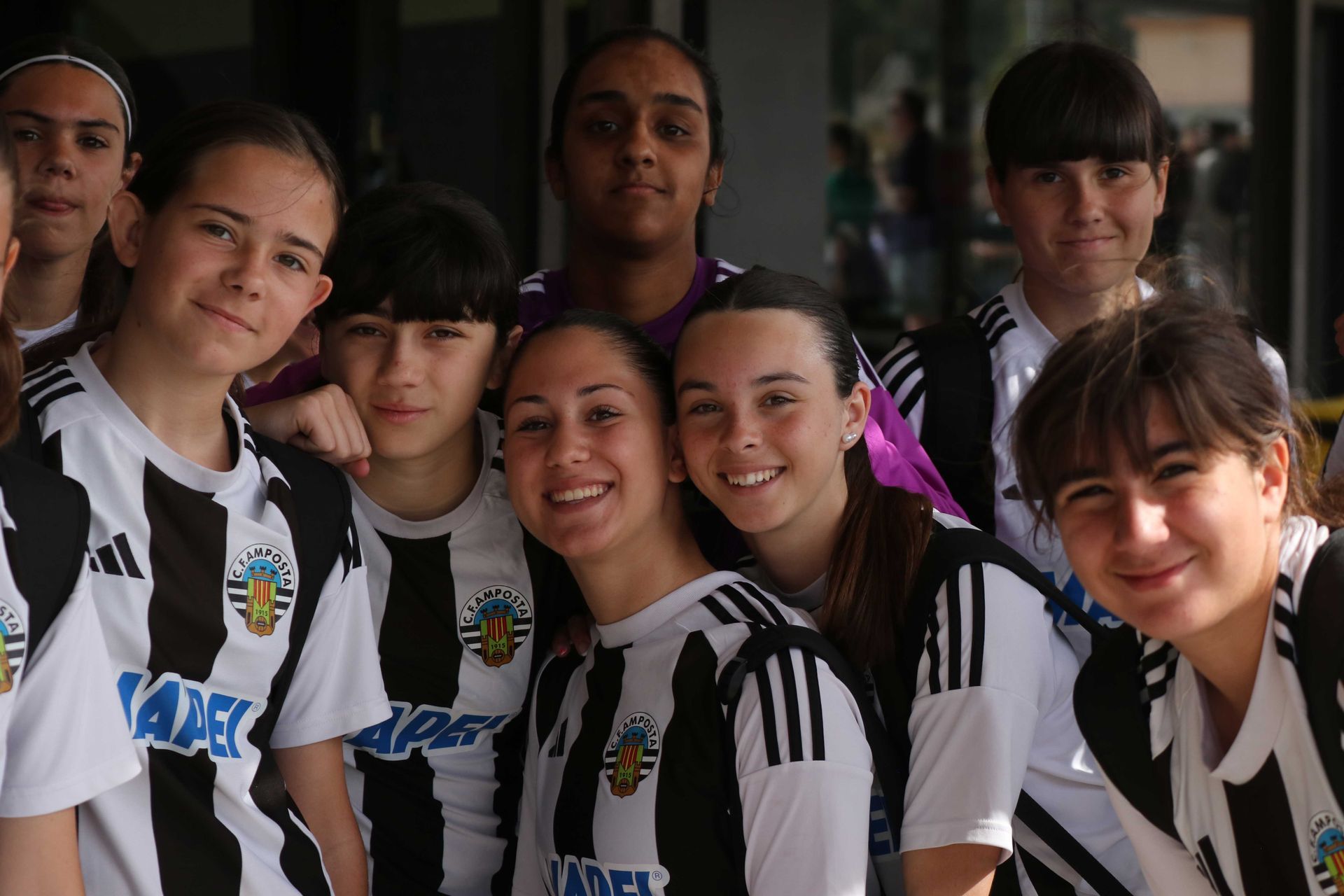 Group of smiling soccer players in black-and-white striped jerseys posing indoors