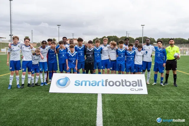 Soccer teams pose on a field in blue and white uniforms, with a referee, and 