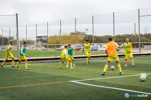 Soccer players in yellow and teal practice passing on a green field.