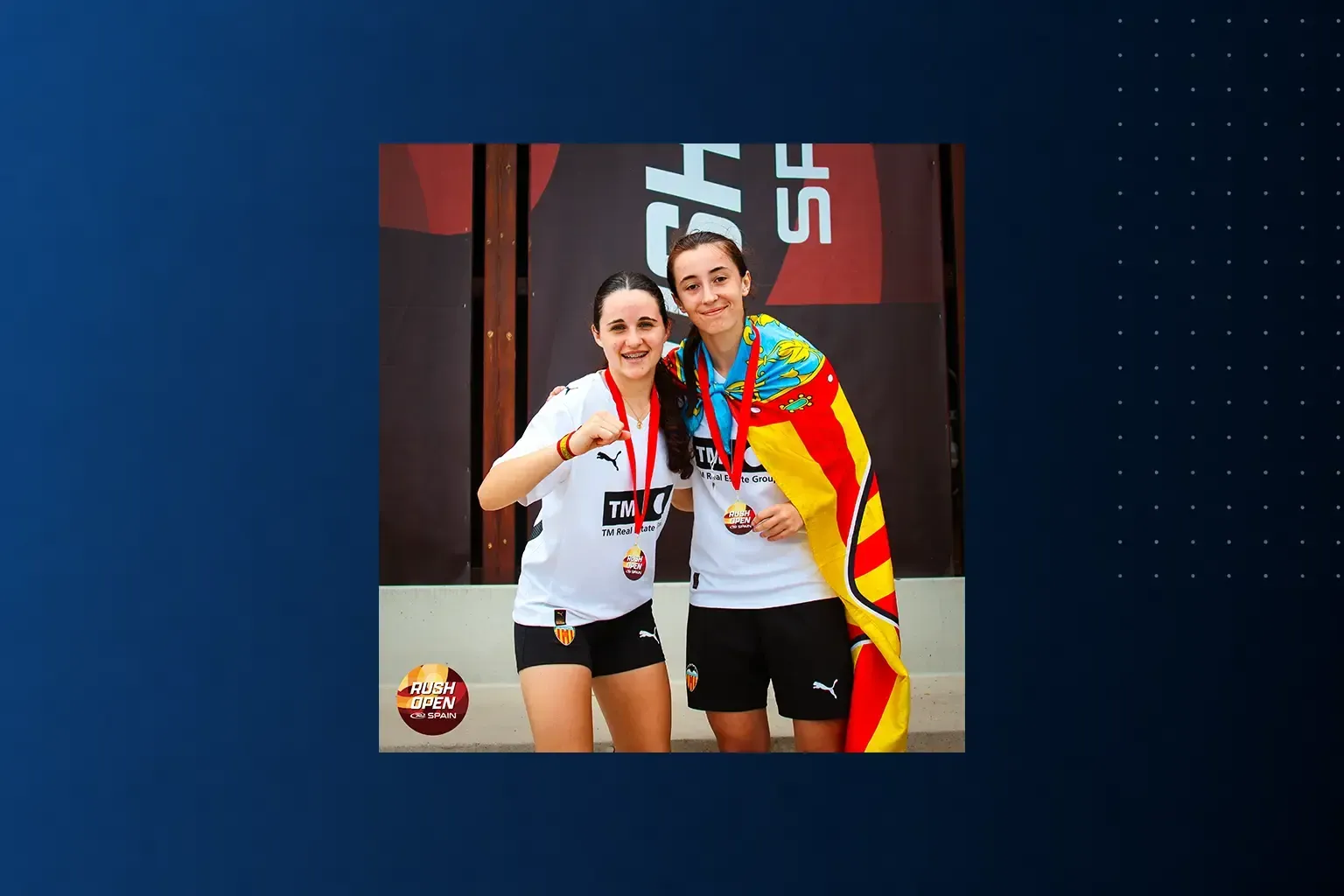 Two smiling athletes posing with medals, one in a white shirt and one in a colorful jacket.
