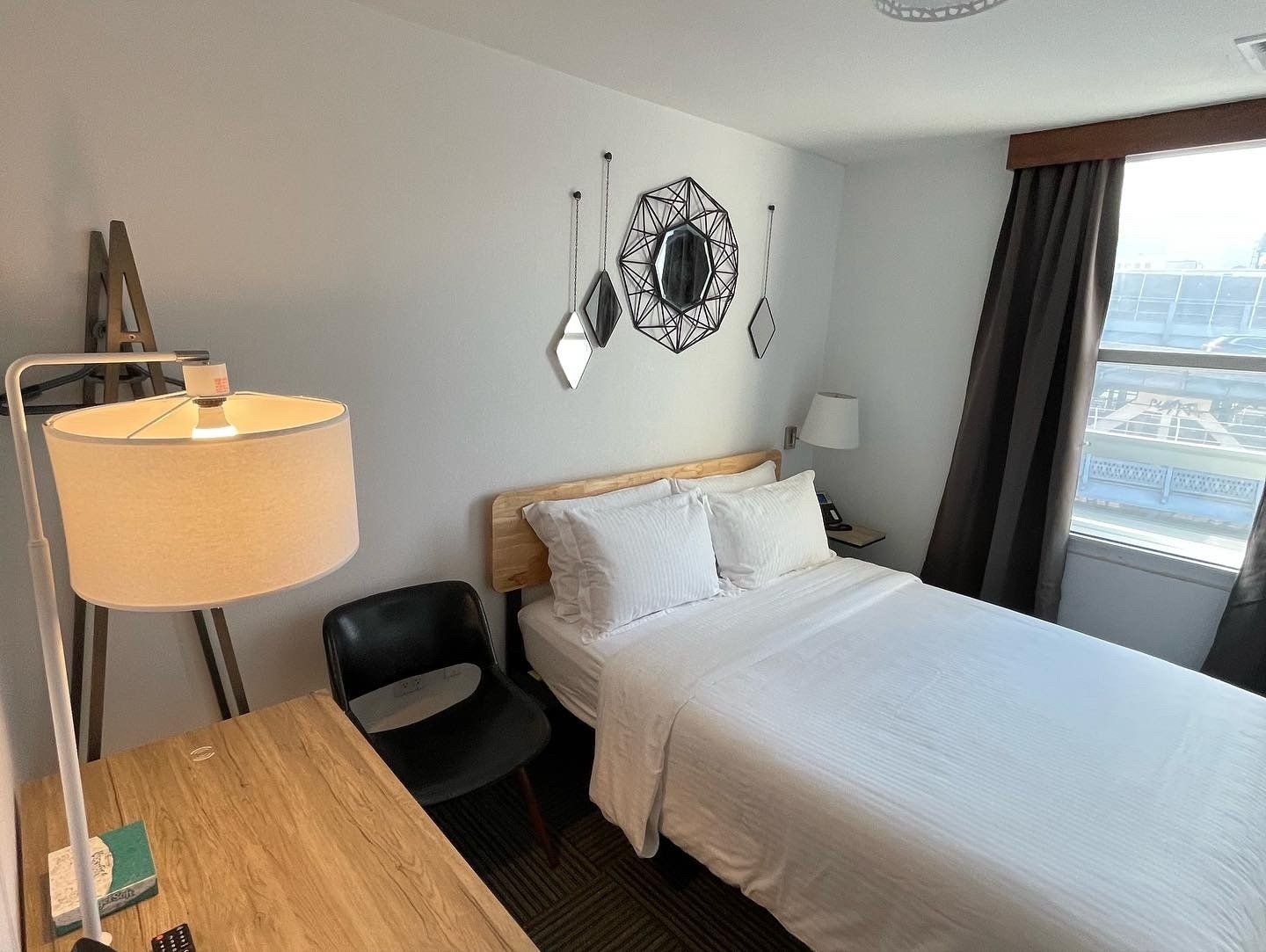 A bedroom with a bed , desk , chair and lamp.