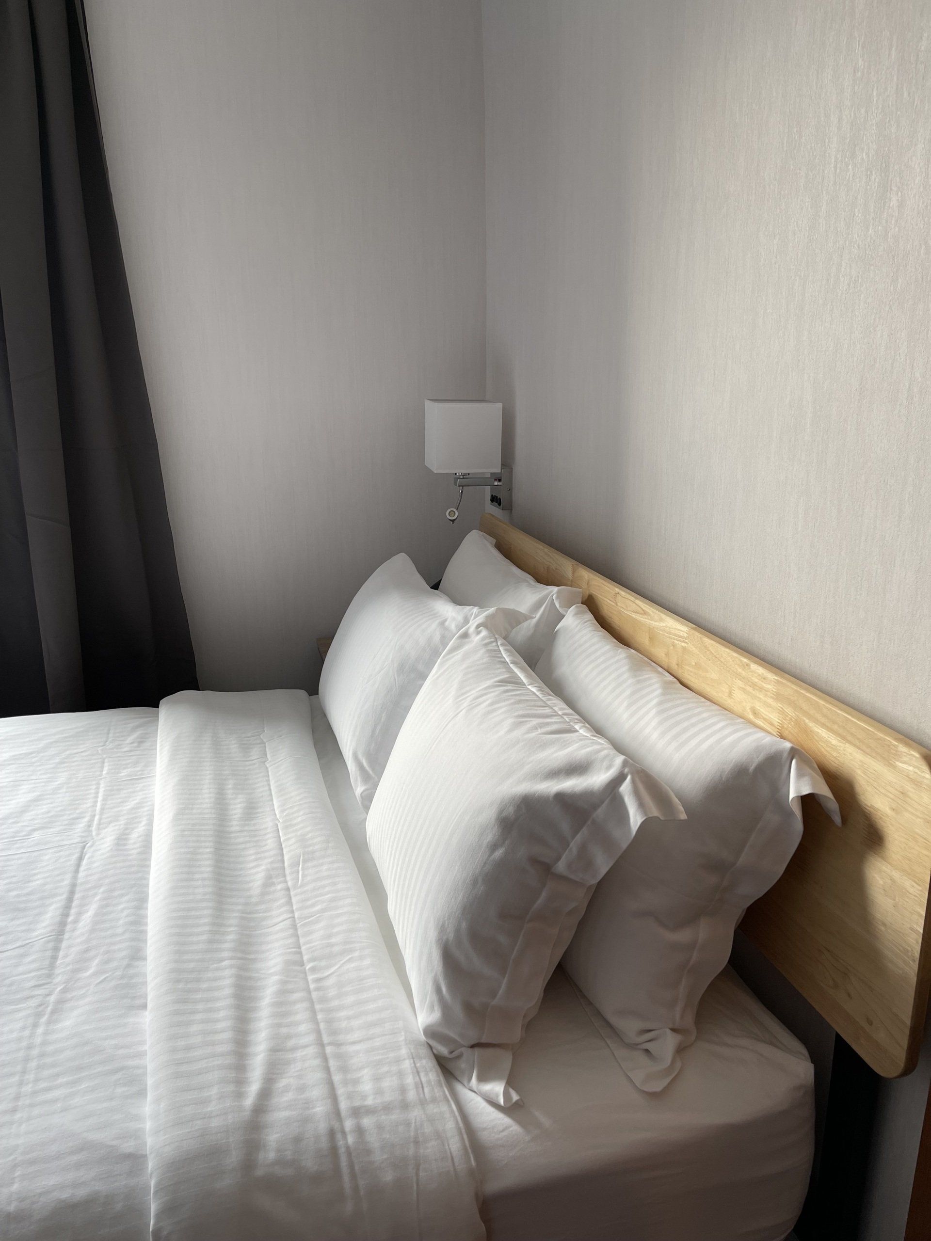 A bed with white sheets and pillows in a bedroom with a wooden headboard.