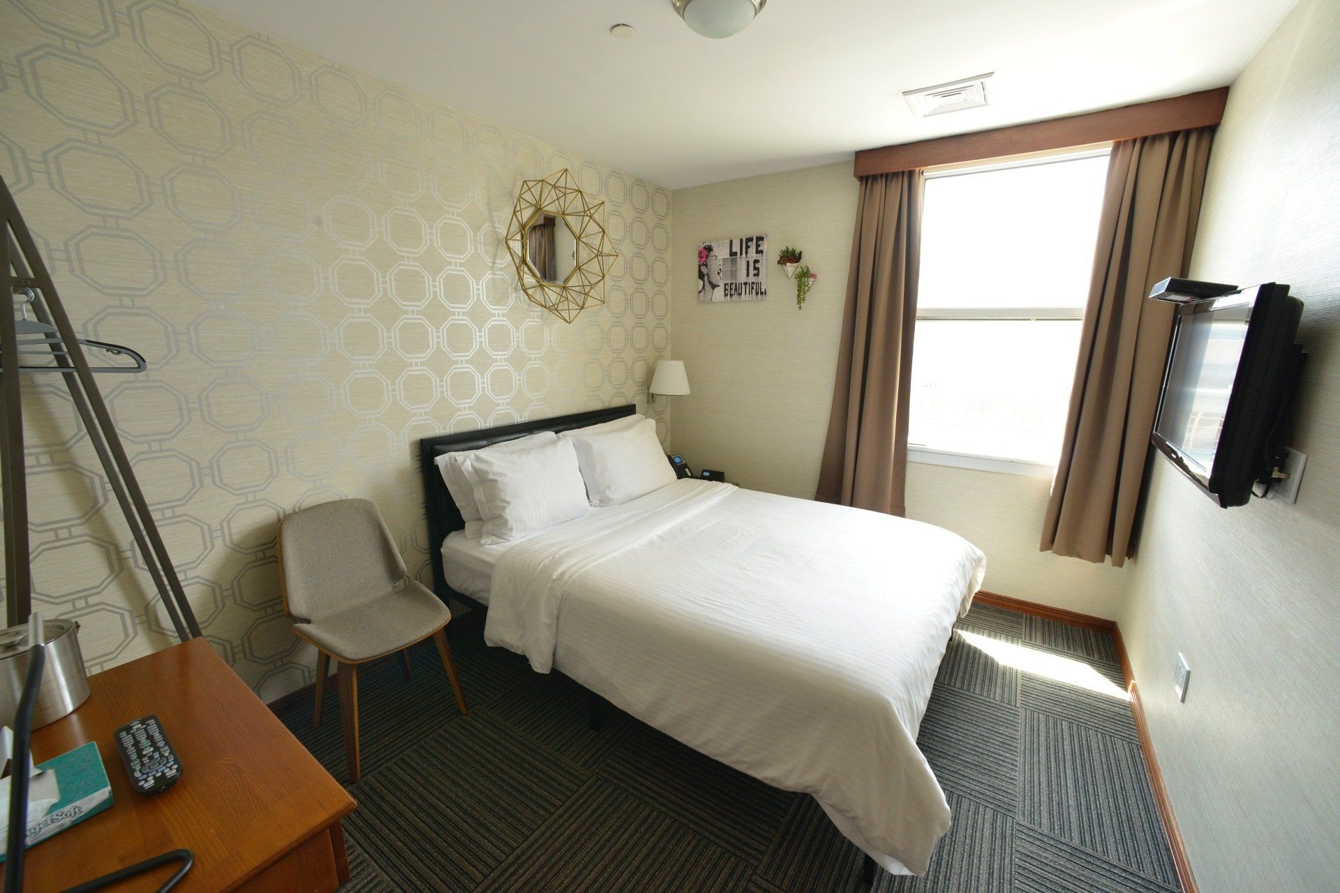 A hotel room with a bed , chair , desk and television.