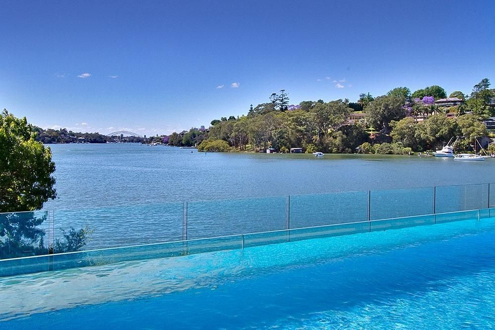 A Large House With A Swimming Pool In Front Of It — Dimension One Glass Fencing In Tuggerah, NSW