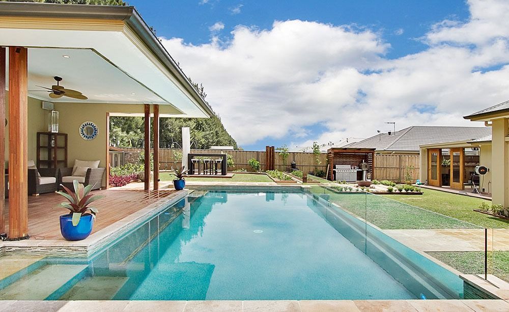 A large swimming pool in the backyard of a house — Dimension One Glass Fencing In Tuggerah, NSW