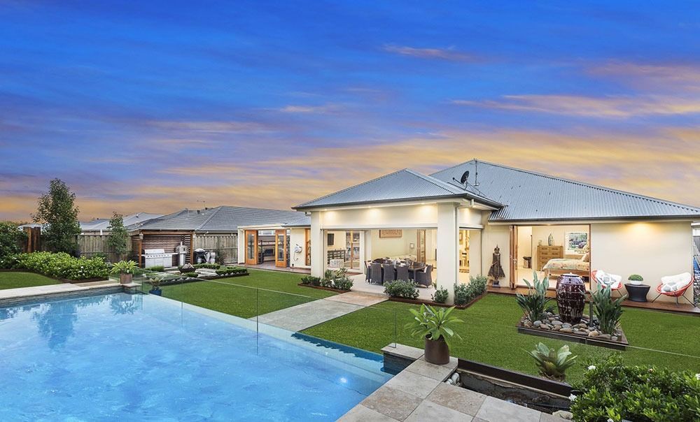 A Large House With A Swimming Pool In Front Of It — Dimension One Glass Fencing In Tuggerah, NSW