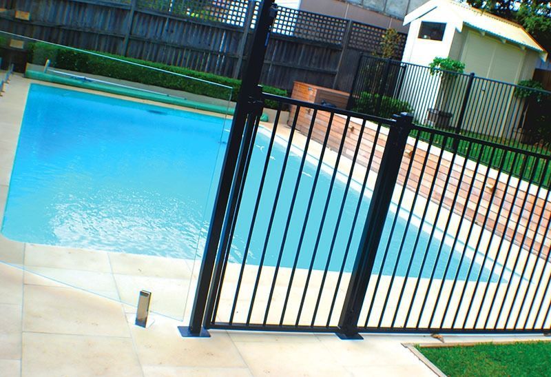 A Black Fence Surrounds a Large Swimming Pool — Dimension One Glass Fencing in Tuggerah, NSW