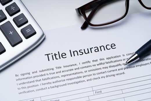 Title insurance document with calculator, glasses, and pen on a desk
