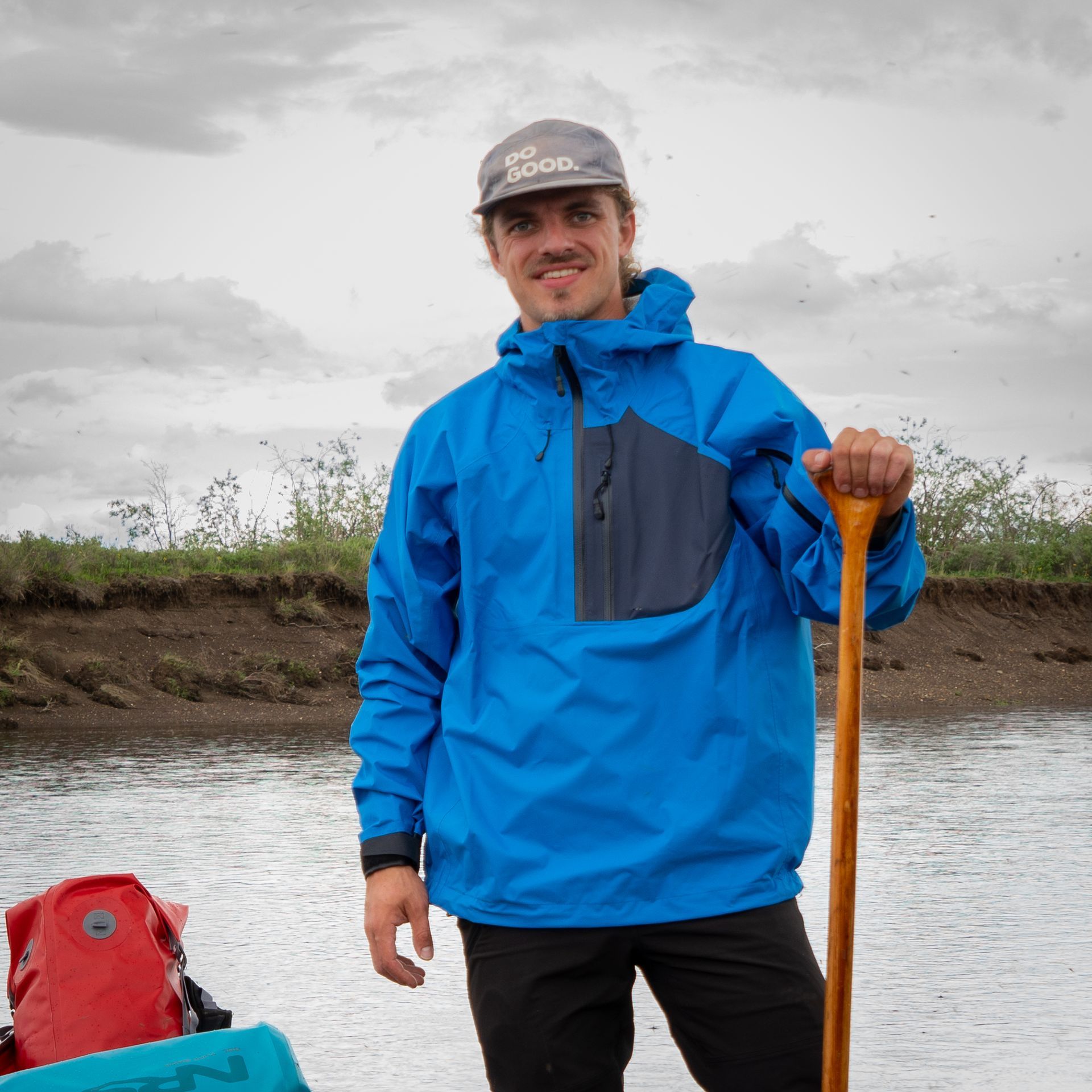 John Gove outdoors in a blue jacket holding a paddle