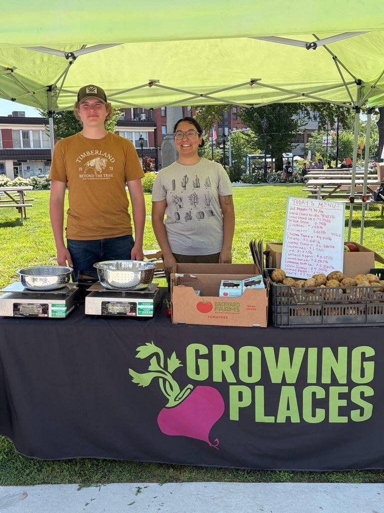Growing Places staff at a farmers market with fresh local produce.
