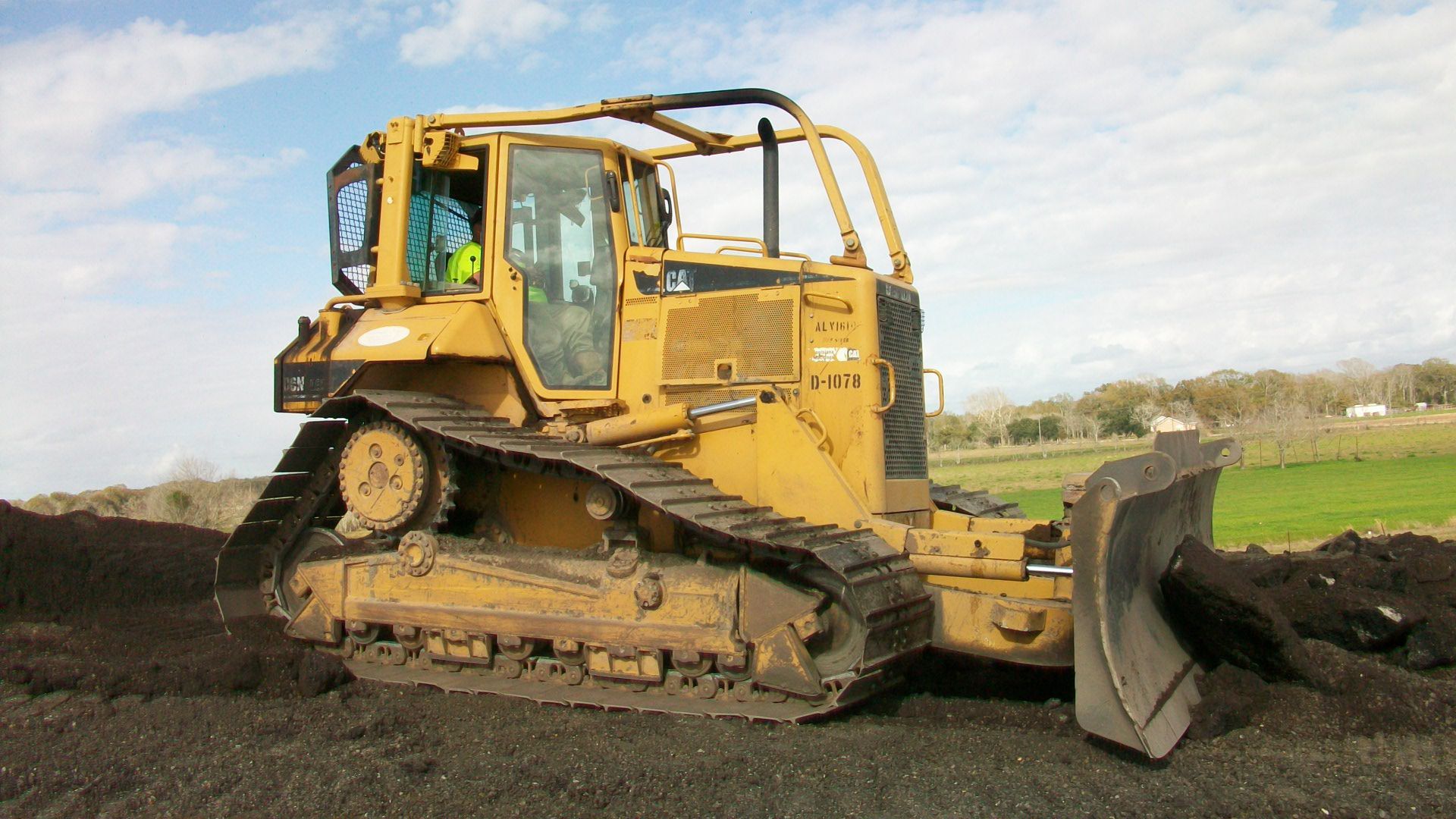 A yellow bulldozer is driving through a dirt field.