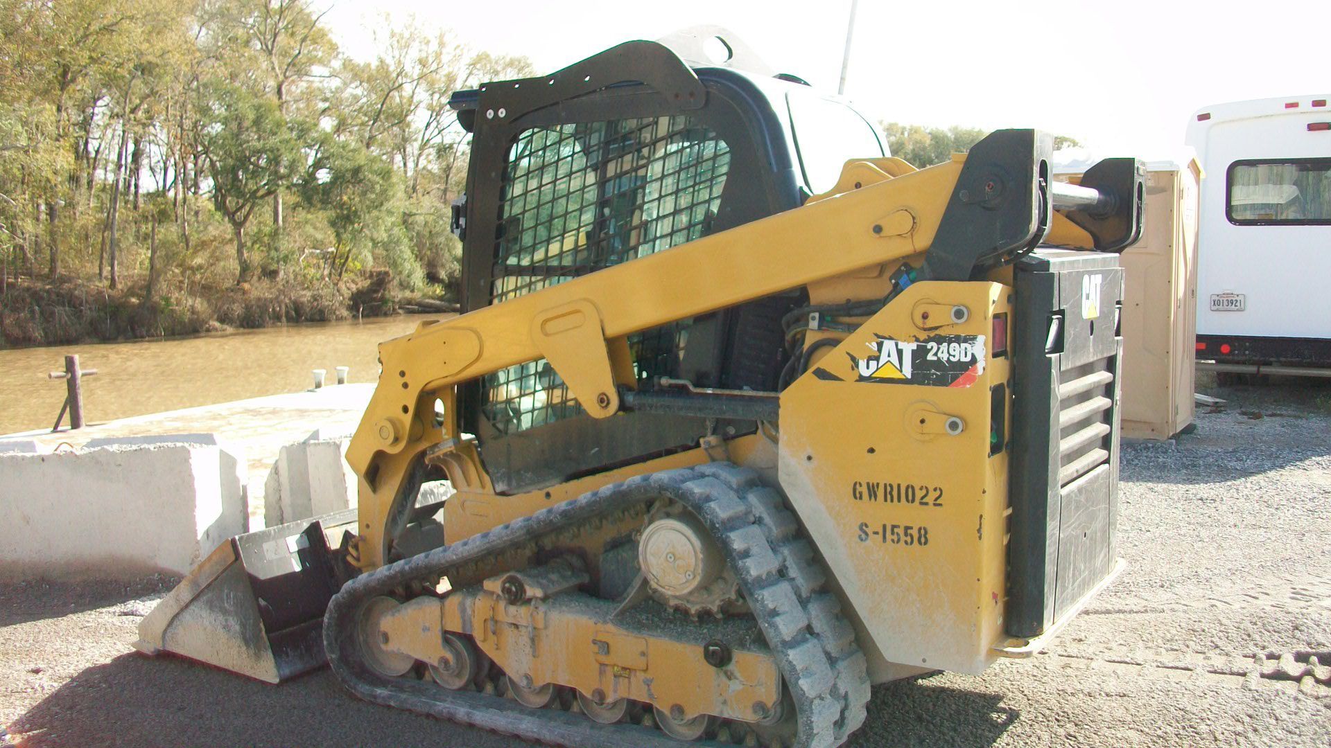 A yellow cat skid steer is parked in a gravel lot.