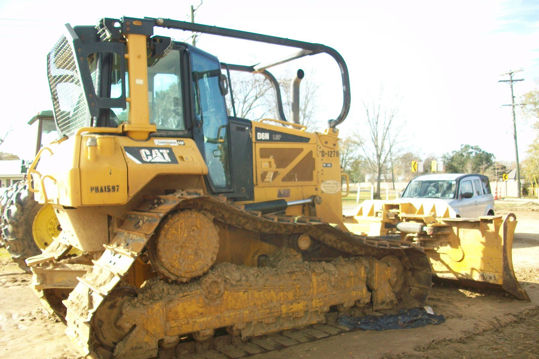 A yellow cat bulldozer is parked in the dirt.