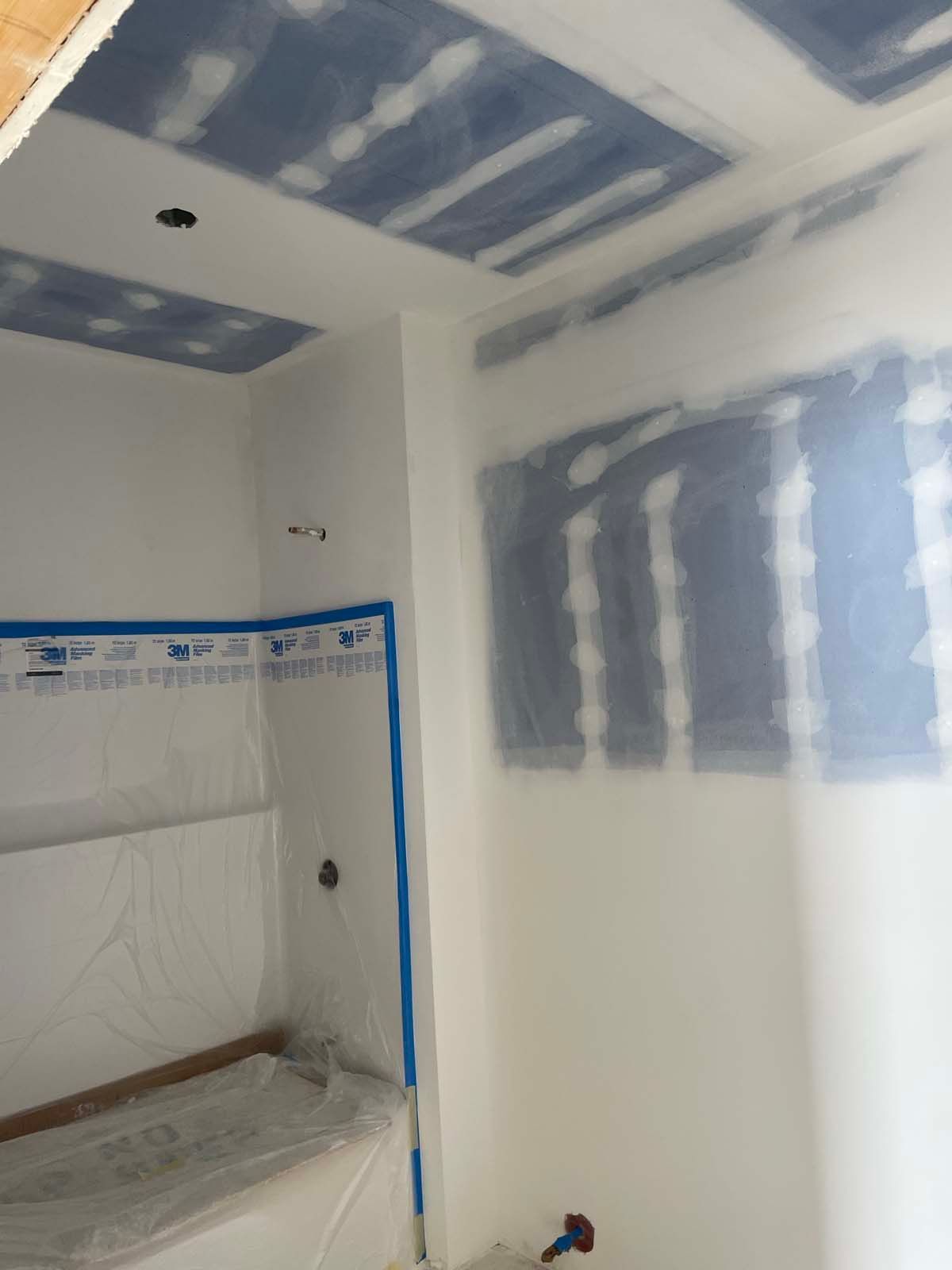 Partially finished room with taped drywall seams, blue joint compound patches, and a built-in bench nook.