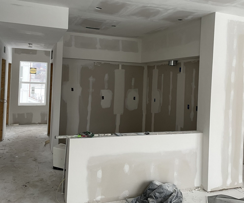 Unfinished interior room with drywall panels, white walls, and a window at the far end