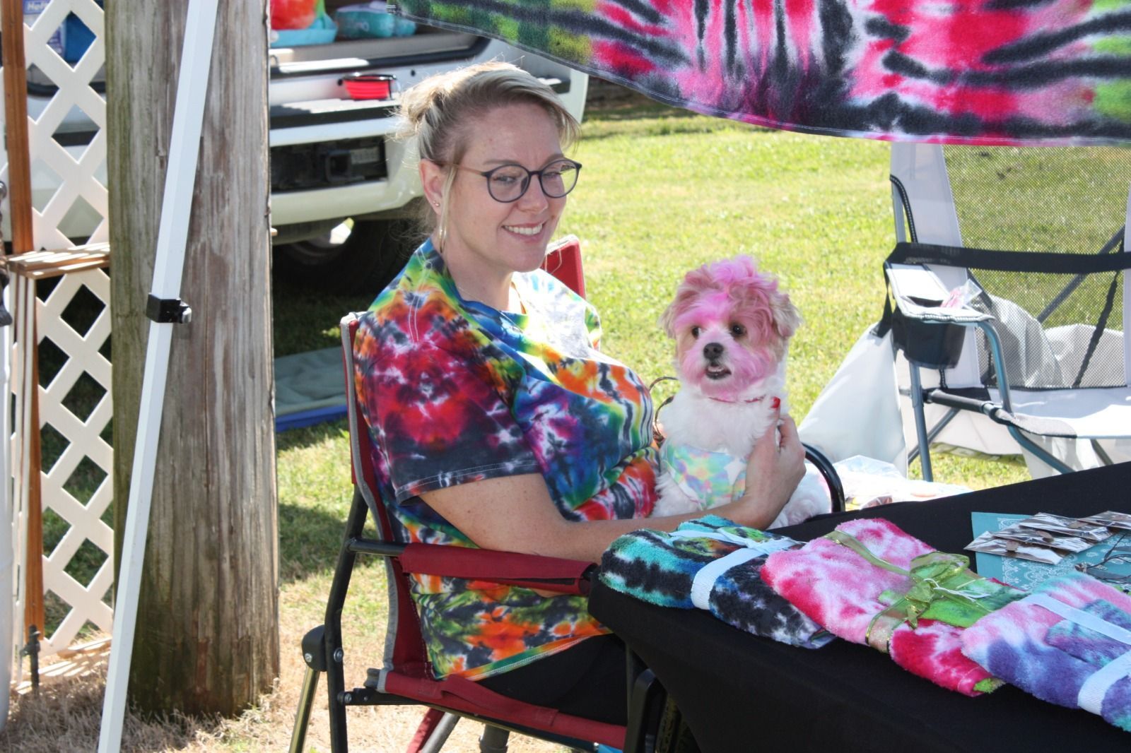 A woman is sitting in a chair holding a pink dog.