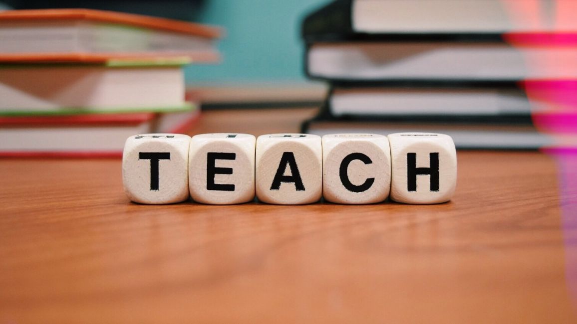 the word teach is written on dice on a wooden table .