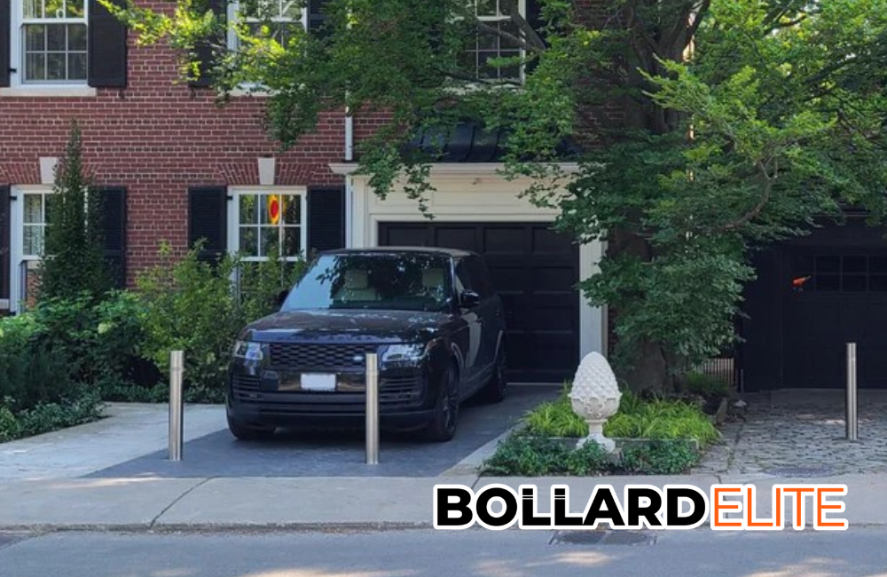 A black range rover is parked in front of a brick house with bollards in place