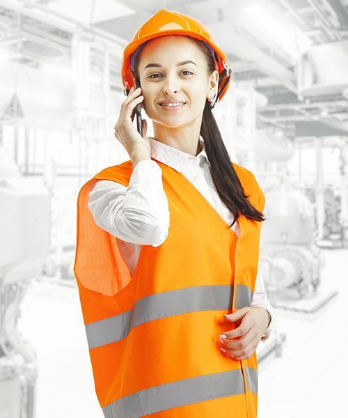 A woman wearing an orange vest and hard hat is talking on a cell phone.