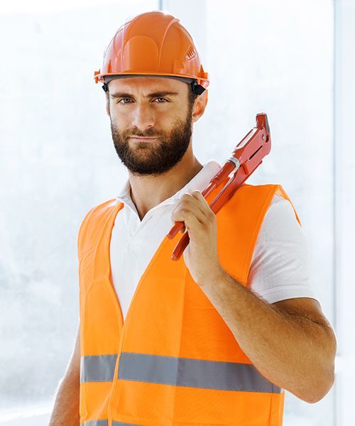 A man wearing a hard hat and an orange vest is holding a wrench.
