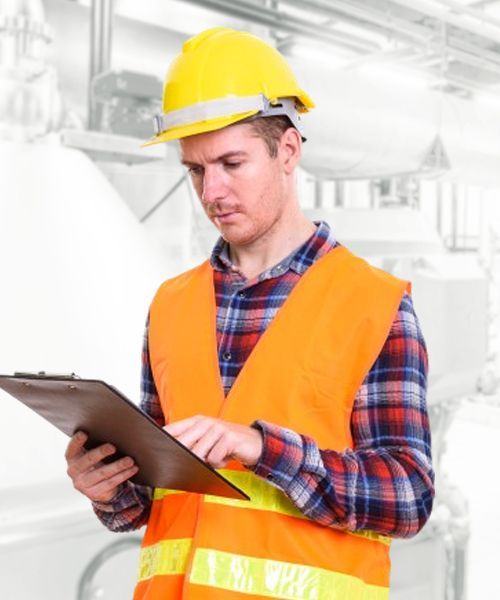 A man wearing a hard hat is looking at a clipboard