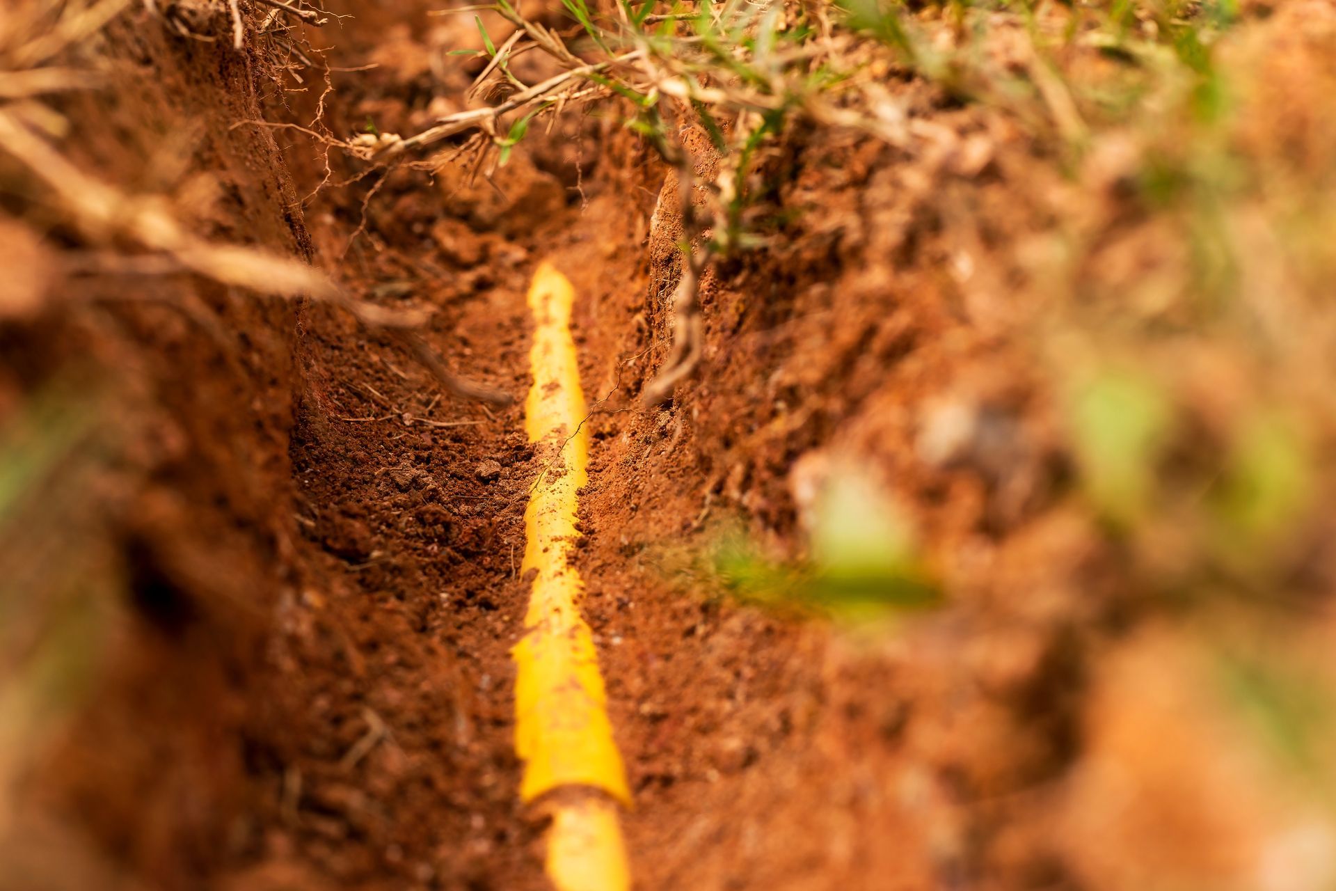 A yellow plastic pipeline for protection of a fibre optic cable buried underground.