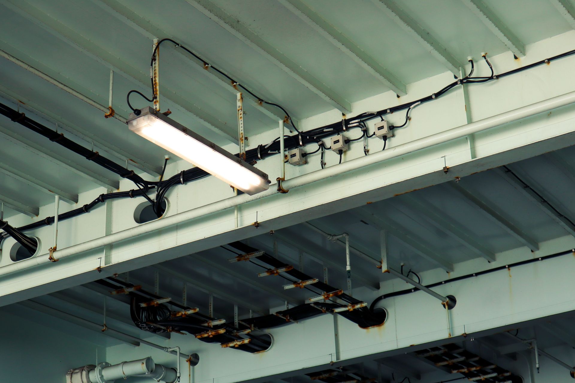 Industrial ceiling with fluorescent light and exposed pipes in a warehouse-like interior