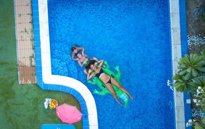 Family relaxing in a blue pool with a green float.
