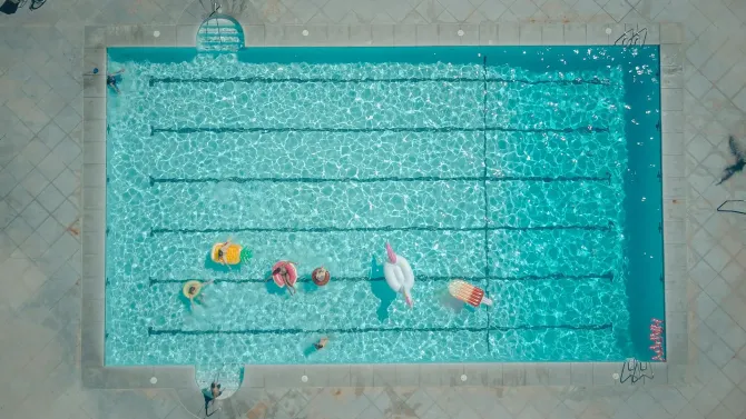Aerial view of swimmers and colorful floats in a pool.
