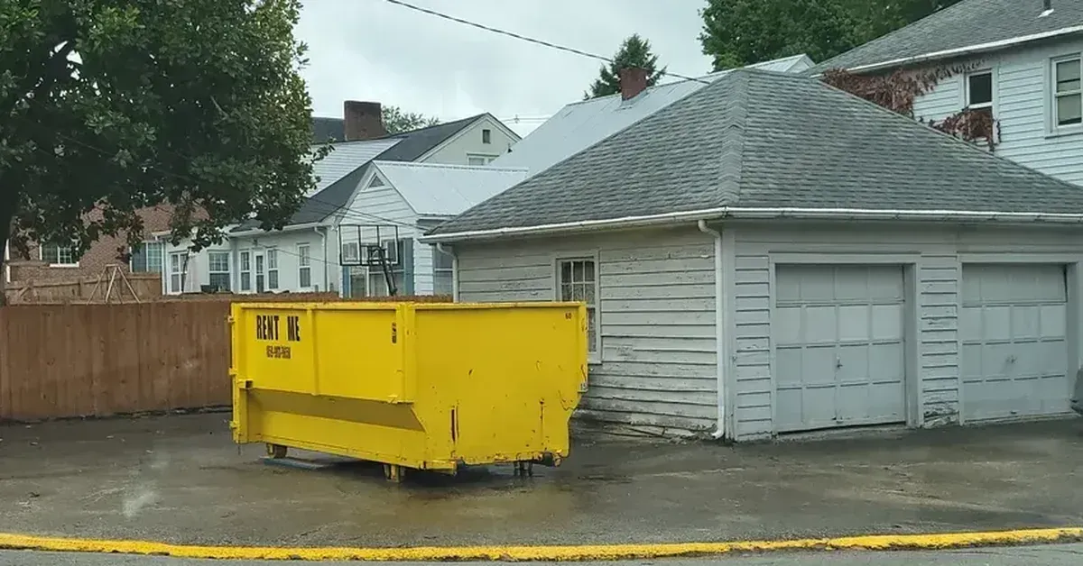 yellow rental dumpster in a driveway for home cleanout