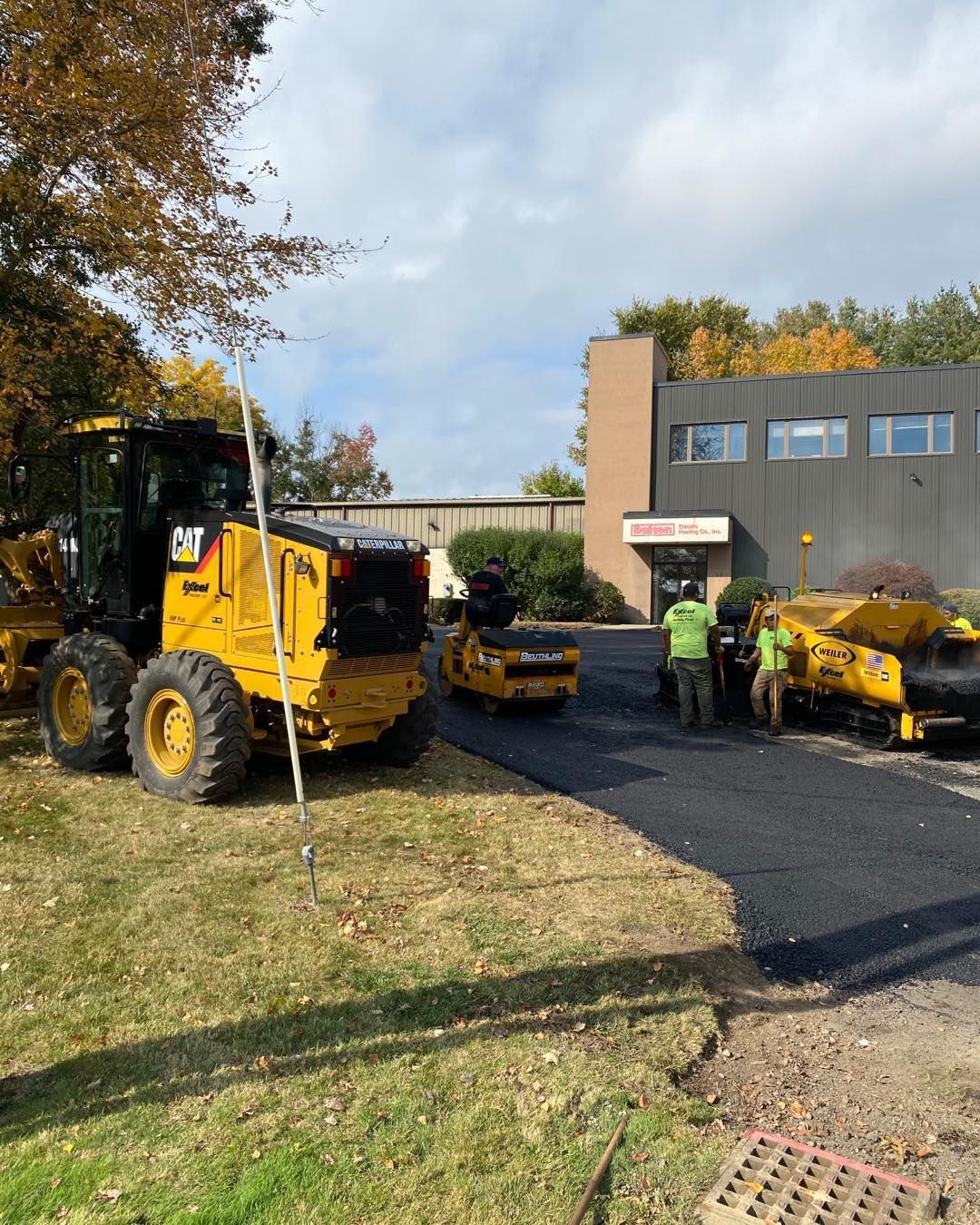 A group of construction workers are working on a road in front of a building.