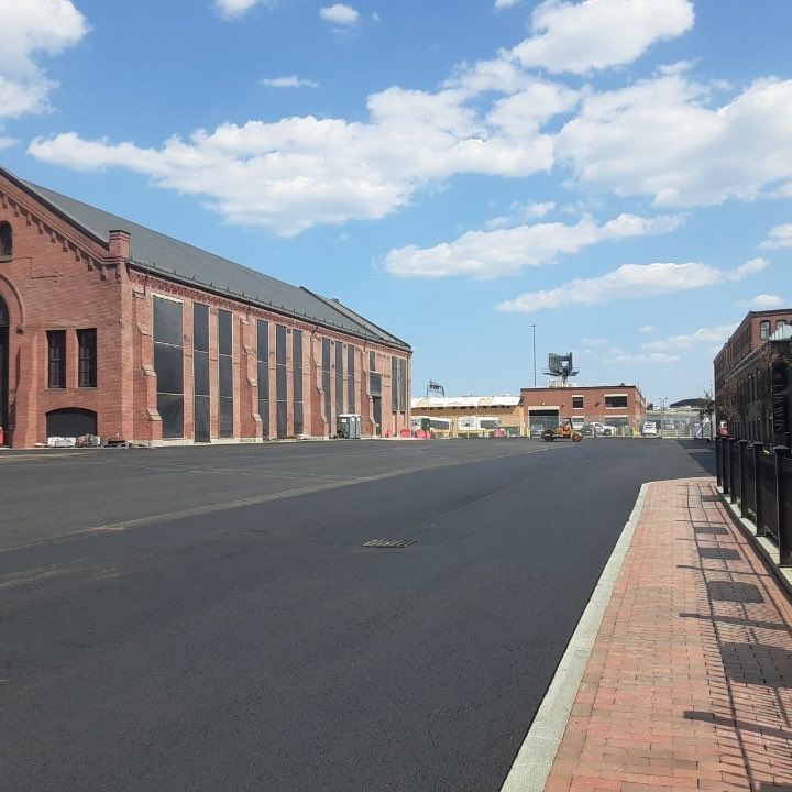 A brick building with a black roof sits on the side of a road