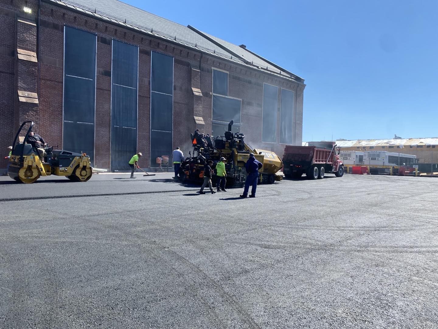 A group of people are standing in a parking lot next to a large building.