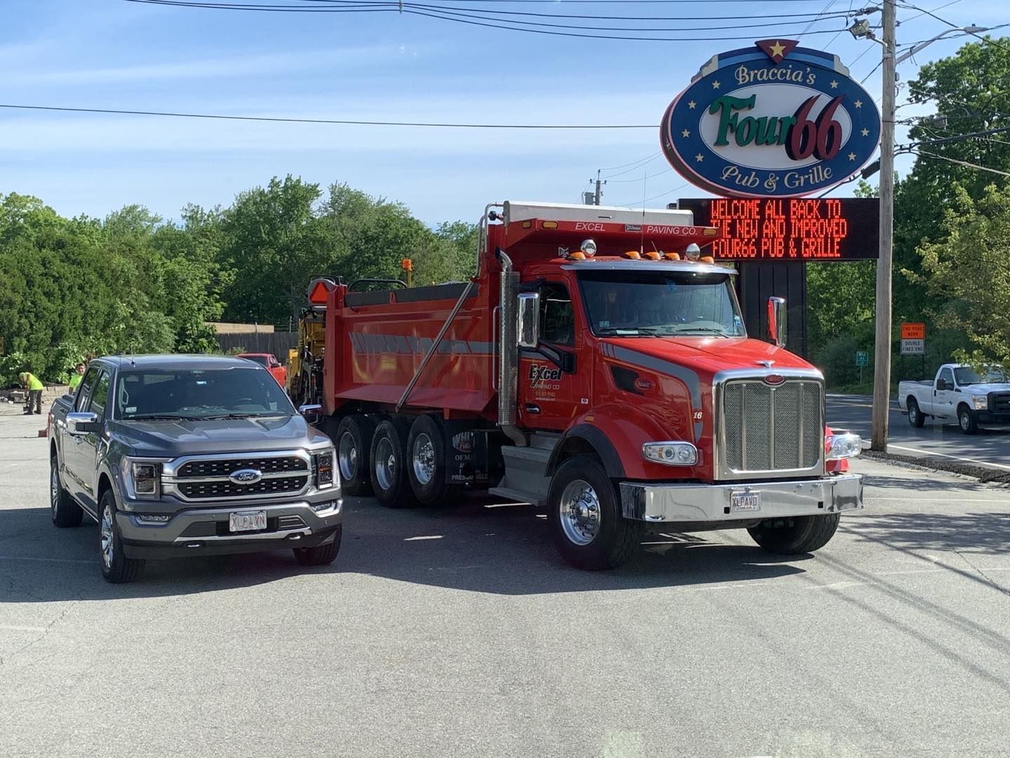 Two trucks are parked on the side of the road in front of a sign that says texas 66