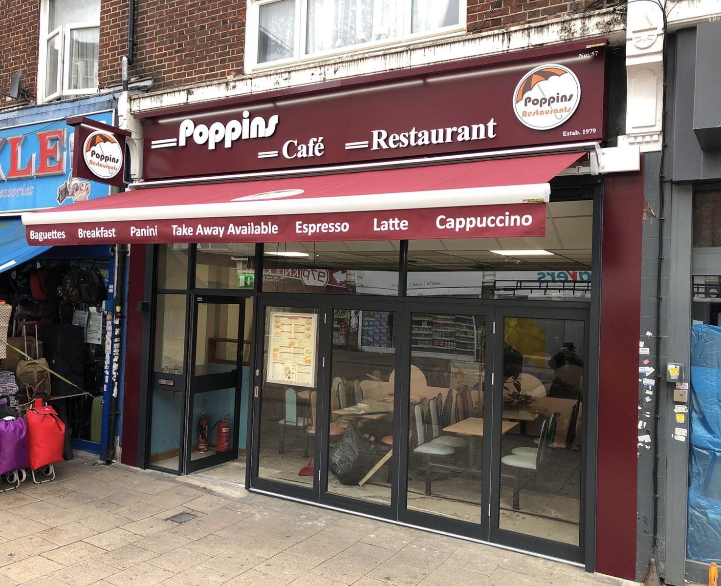 Poppin café-restaurant storefront with red awning and glass entrance on a city street