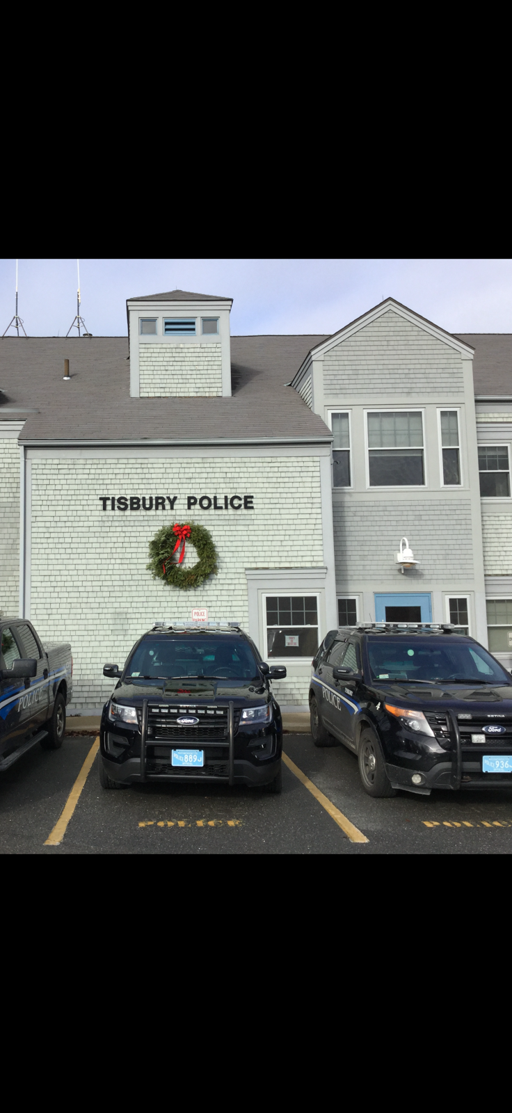 Two police cars are parked in front of a police station.