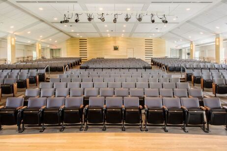 A large auditorium with rows of empty seats and a stage.