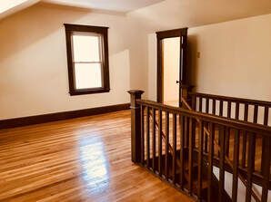 An empty room with a wooden staircase and a window.