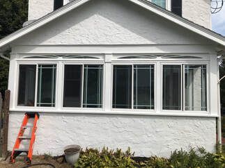 A white house with a lot of windows and a ladder on the side of it.