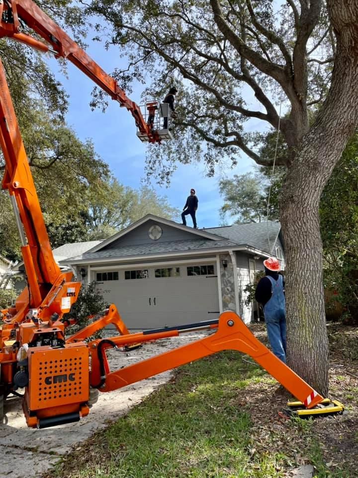 A man is standing on the roof of a house with a crane.