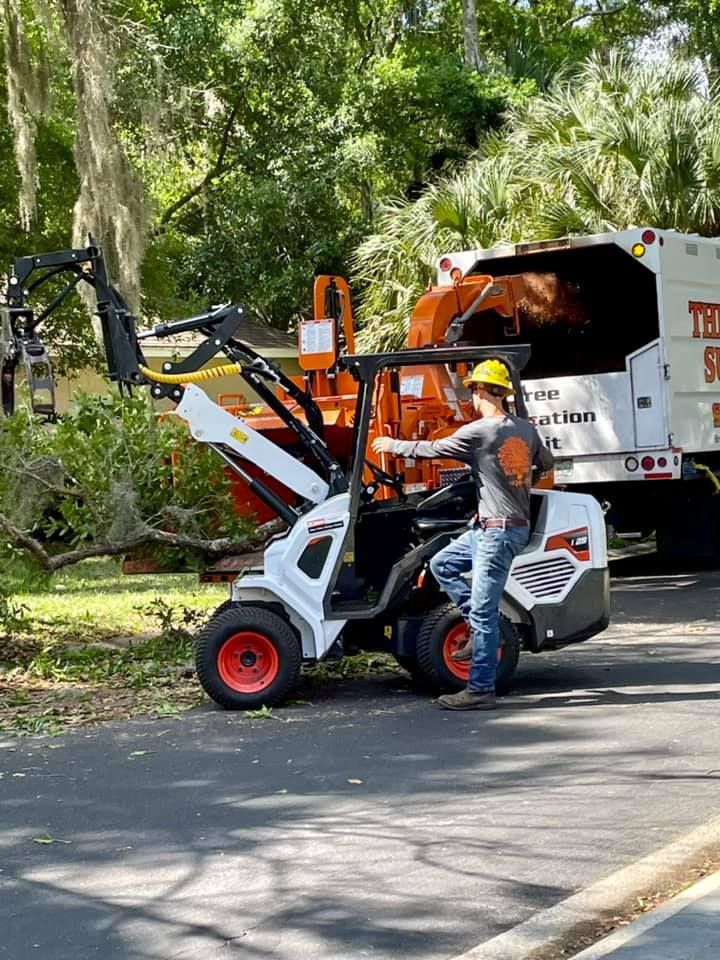 A man is standing next to a forklift on the side of the road.