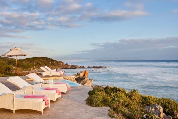 Lounge chairs with pink towels overlook the ocean at a resort.