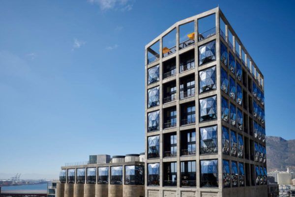 Modern concrete building with large, reflective windows under a blue sky.