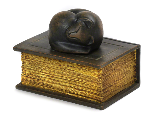 Black curled cat sculpture on a gold-edged book-shaped base