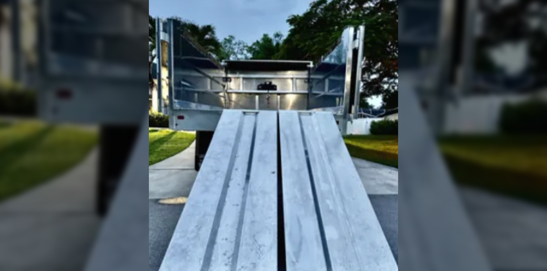 Wooden bridge walkway leading to a small platform in a park, surrounded by trees and greenery