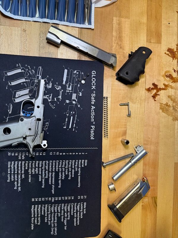 Pistol disassembly on a workbench, with parts, tools, and an exploded parts diagram.