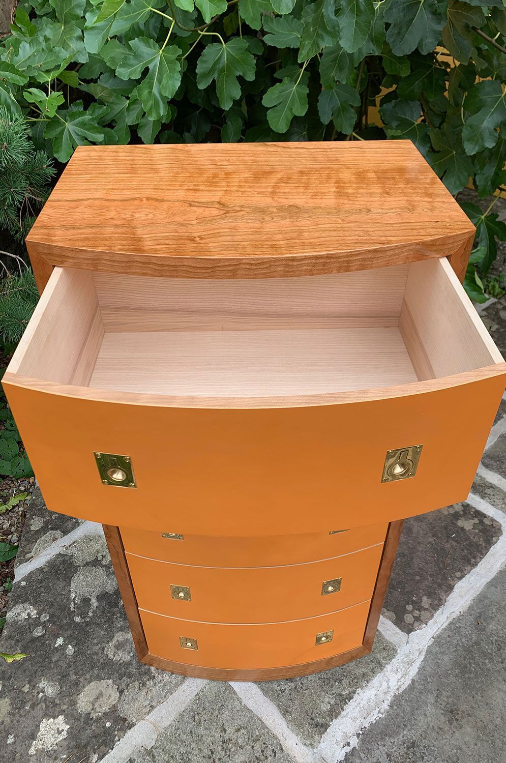 A handcrafted wooden art cabinet with the drawer open.