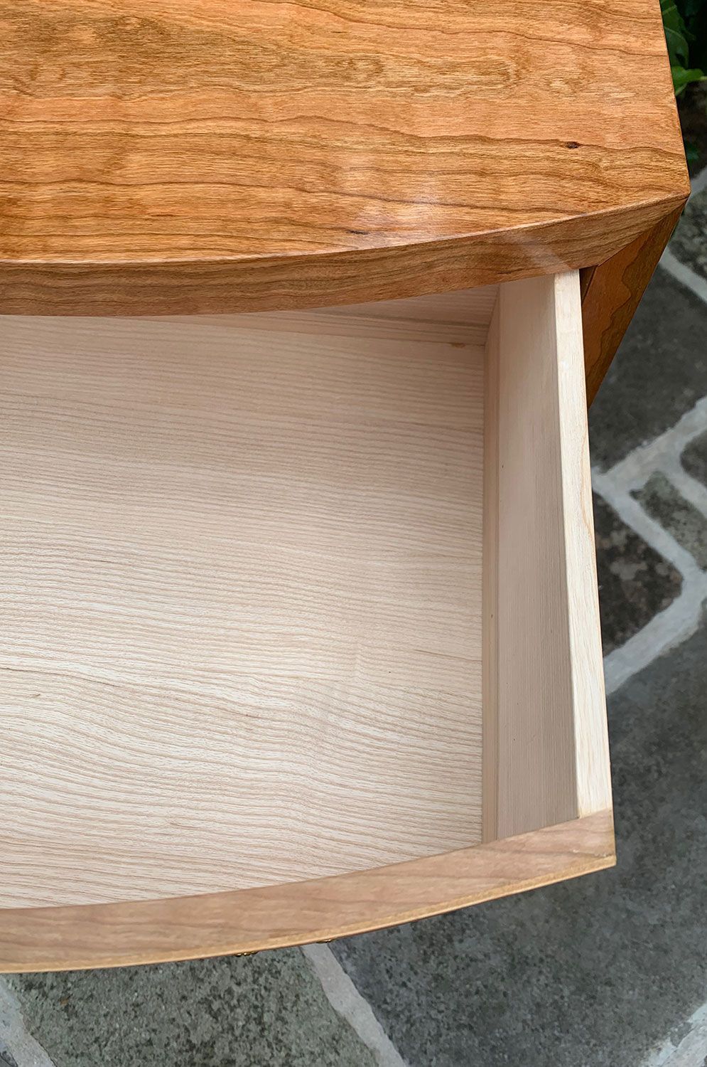 A close up of an empty handcrafted wooden drawer on a wooden table.